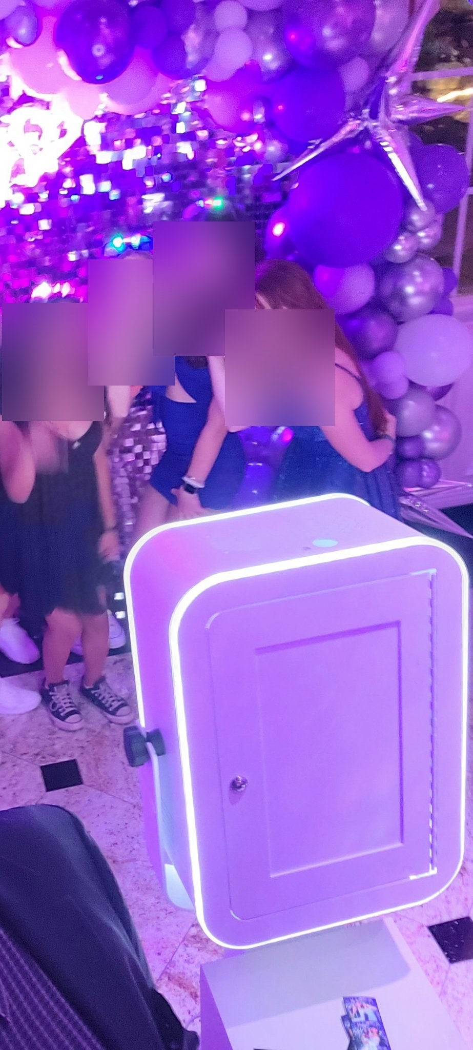 Guests posing with the photo booth under purple party lighting
