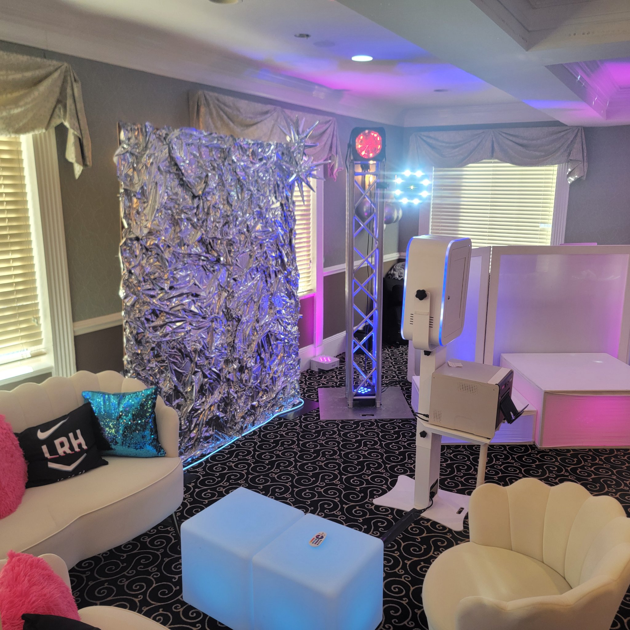 Complete photo booth setup with silver backdrop, lighting truss, and printer