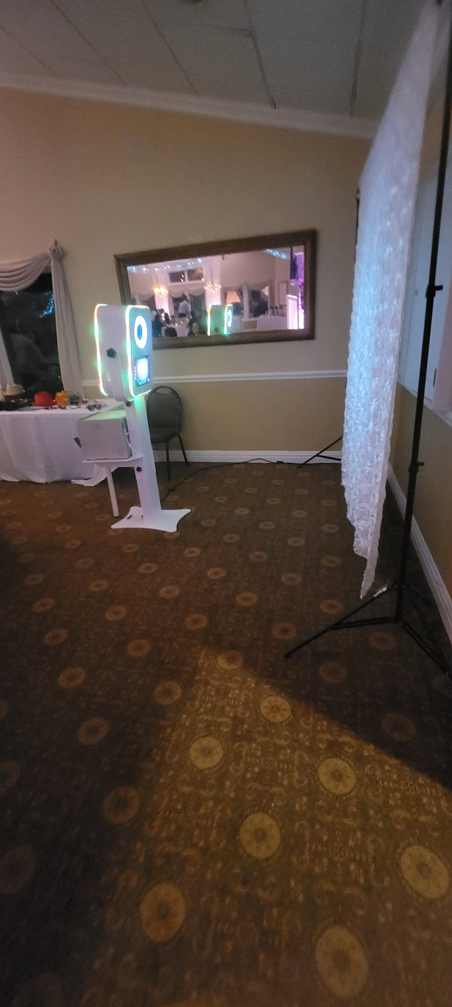 Photo booth kiosk beside an elegant white backdrop, set and ready