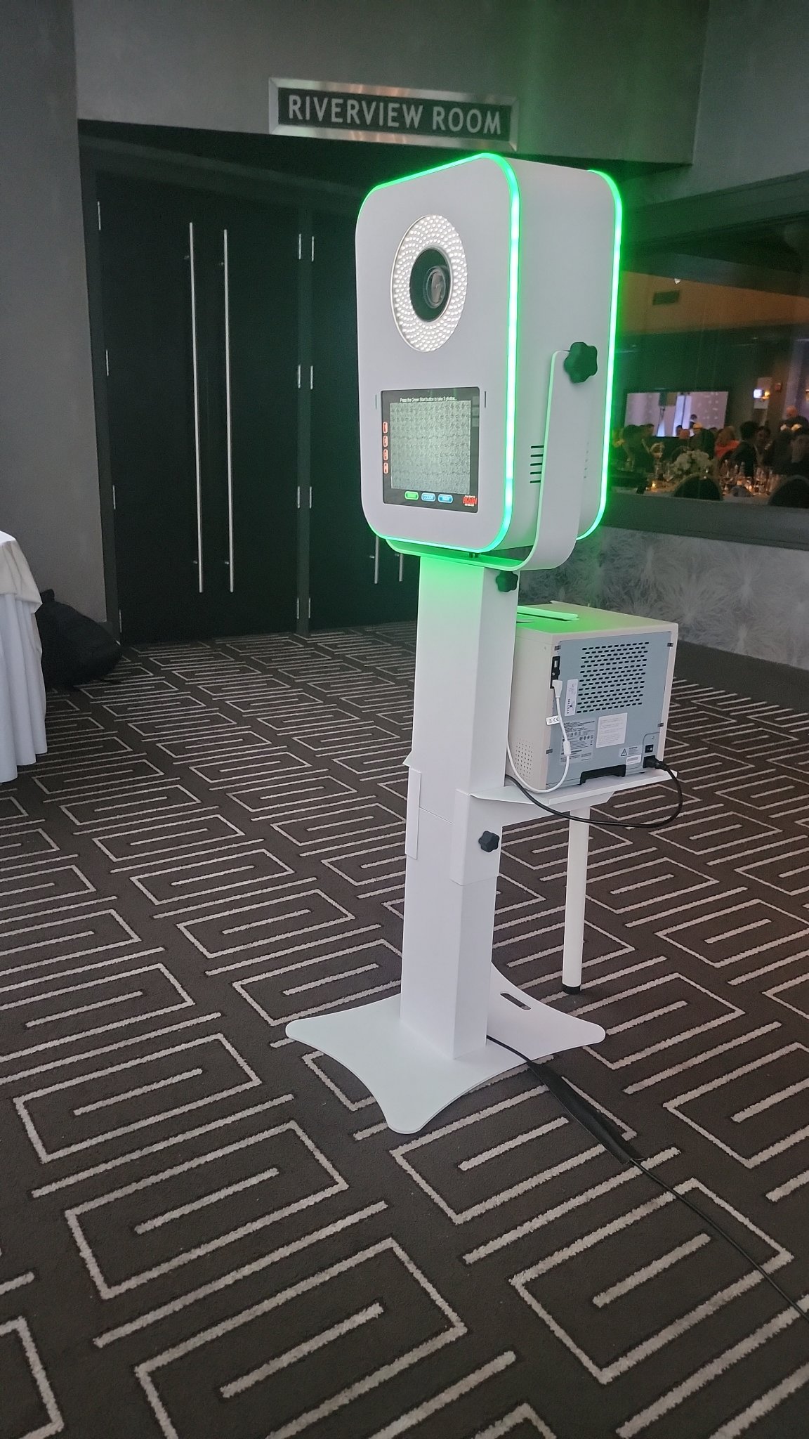 Photo booth kiosk set up at a venue celebration with artwork on the walls