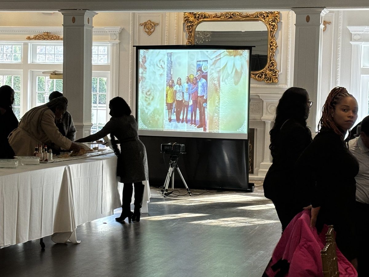 Banquet room with memorial tribute playing on a projector screen as guests gather